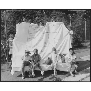 Young children posing around a large floor plan of an afterschool building