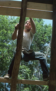 Peter Jensen installing roof sheathing on western roof slope at the Moon Barn Raising at entrance to Hopkins Forest on 2 August 1975.