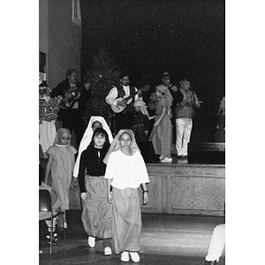 Children dressed as shepherds exit the stage during a Christmas pageant.