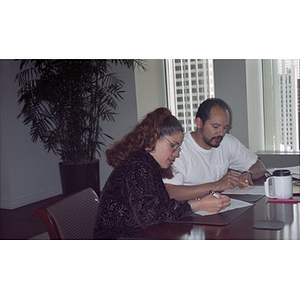 Two board members fill out worksheets during a board training session.