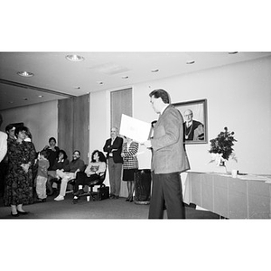 Unidentified man reading from a certificate during a presentation ceremony.