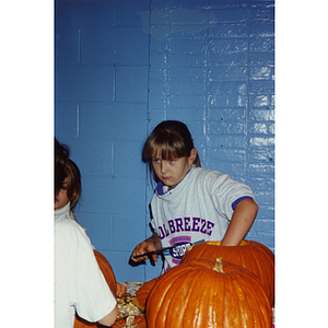 A girl carves a pumpkin at a Halloween event