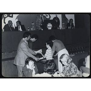 A man presents a certificate to a boy and shakes his hand at a Boys' Clubs of Boston Awards Night