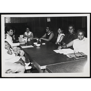 A group of women and a child sit at a table during a Mothers' Club meeting