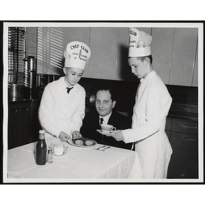 Two members of the Tom Pappas Chefs' Club serve Mr. Cerrone at a table