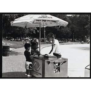A teenage boy operating an ice juice cart talks to two boys on Boston Common