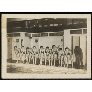 A group of teenage boys pose for a group shot poolside in a natorium