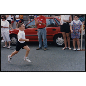 A boy runs past spectators during the Bunker Hill Road Race