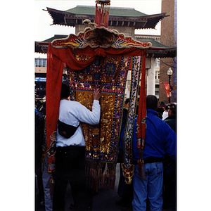 Man walks with a decorative banner in a parade celebrating the Chinese New Year in Boston's Chinatown