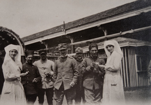 Two Red Cross workers offering cigarettes to five soldiers in front of a canteen