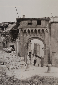 View of a man walking into a town through a damaged archway