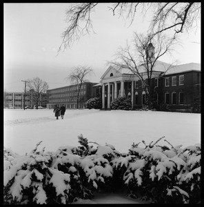 Students walking out of Goodell Library on a snowy day, with Bartlett Hall in the background