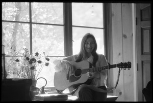 Judy Collins seated in a window at Joni Mitchell's house in Laurel Canyon, playing guitar