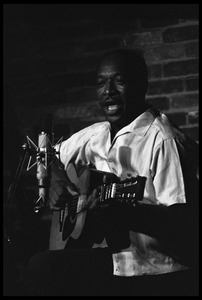 Josh White performing on guitar in a coffeehouse