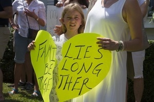 Mother and daughter pro-immigration protesters in front of the Chatham town offices building holding a sign shaped like a broken heart reading 'Families belong together': taken at the 'Families Belong Together' protest against the Trump administration's immigration policies