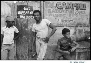 Jimmy Cliff (center) standing by a sign 'Beware of tigers and bad dogs' near his old home on Spanish Town Road