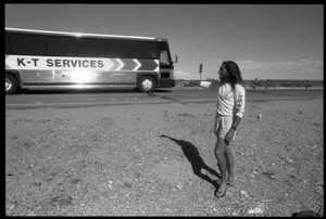 Peace encampment activist waving at a passing vehicle on the road near the entrance to the Nevada Test Site