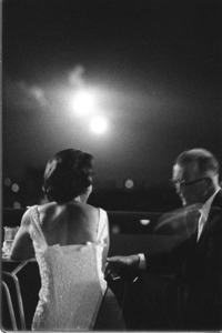American couple during a cocktail party on the roof of the Saigon Caravelle Hotel watching flares dropped by U.S. aircraft over firefight in suburbs.