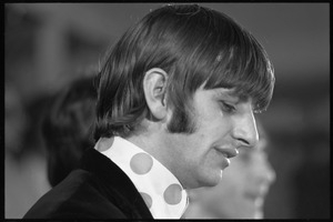 Ringo Starr seated at a table during a Beatles press conference: close-up in profile
