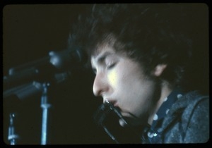 Bob Dylan performing on stage, playing harmonica