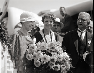 Amelia Earhart reception: Earhart with bouquet of flowers, standing between her mother (left) and acting Mayor Edward M. Gallagher, in front of her Lockheed Vega 5b airplane