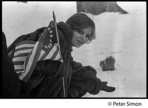 Women with an American flag (with circular field of stars), leaning down in the snow: Resistance antiwar rally