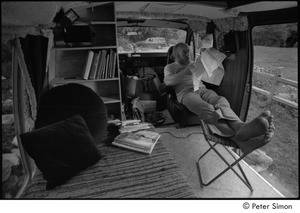 Ram Dass in his van: Ram Dass with his feet up, studying a map