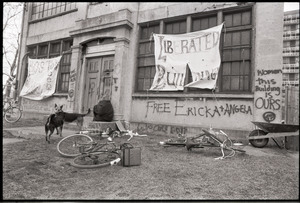 Women's occupation of the Architectural Technology Workshop, Harvard University: two dogs, occupier, and bicycles outside ATW, graffiti and signs announcing "Liberated building" and "Women, this building is ours"