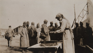 Red Cross worker preparing food for soldiers standing nearby