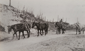 Two soldiers with horses walking along a road past damaged trees