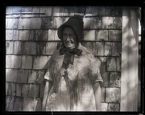 Abbie Loring in Quaker attire, posed in front of shake-sided house