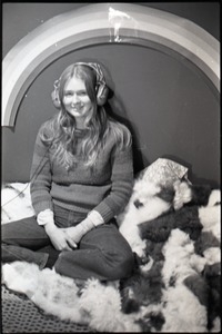 Lynn Smith sitting on faux fur blanket, modeling Koss headphones