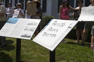 Hand-drawn 'Families belong together' sign laid over historical marker in front of the Chatham town offices building : taken at the 'Families Belong Together' protest against the Trump administration's immigration policies