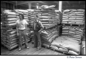 Managers in a stockroom at Erewhon Food Coop warehouse, Farnsworth Street, with bags on pallets (at right may be Tyler Smith, President of Erewhon)