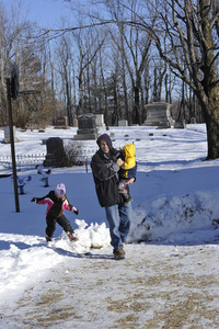 Parent and young children walking through snow in front of the Center Cemetery in New Salem center