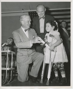 Bruce Barton handing diploma to young girl wearing braces and crutches