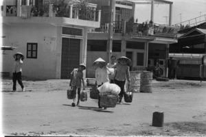 Women leaving the area with belongings during street fighting; Saigon.