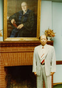Photograph of Ma Qiwei under painting of President Laurence L. Doggett