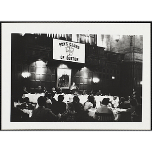 Guests listen as a man speaks at the podium during the "Recognition Dinner at Harvard Club"