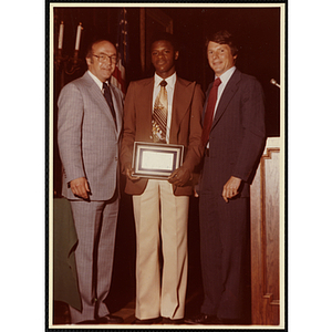 Carlton Burke receives an award from Robert Cleary, Overseer of the Boys' Clubs of Boston, at left, and an unidentified man