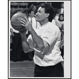 Former New England Patriot Tim Fox holding a basketball and looking up at a fund-raising event held by the Boys and Girls Clubs of Boston and Boston Celtics