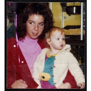 A young woman holding a baby girl and looking off to her right at a joint Charlestown Boys and Girls Club and Charlestown Against Drugs (CHAD) event