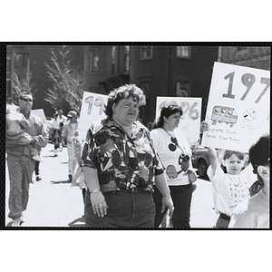 A woman walking beside a girl holding up a parade sign during the Boys and Girls Clubs of Boston 100th Anniversary Celebration Parade