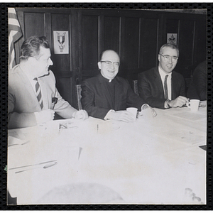 Board of Directors Thomas E. Leggat (right) and two other men sit at a table during a Dad's Club banquet