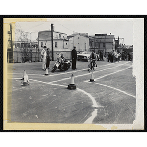 A boy rides a bike on a chalk-lined test track as a police officer looks on