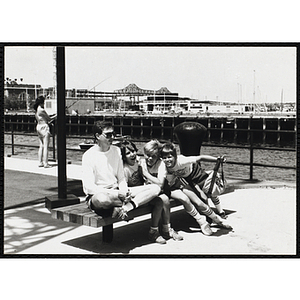 Three children sitting on a bench next to their counselor at the Charlestown Navy Yard