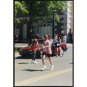 A woman runs past cheering spectators during the Battle of Bunker Hill Road Race