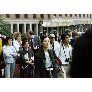 Chinese Americans and other concerned citizens facing right, listening to a speaker at the rally for Long Guang Huang in City Hall Plaza in Boston, with three policemen observing the event in the background