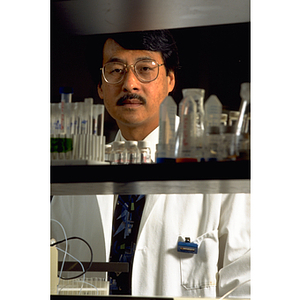 Ban-An Khaw, a professor in the Department of Pharmaceutical Sciences, surrounded by beakers in a laboratory
