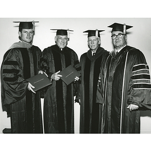 Two honorary degree recipients stand with the chairman of the Board of Trustees and President Knowles